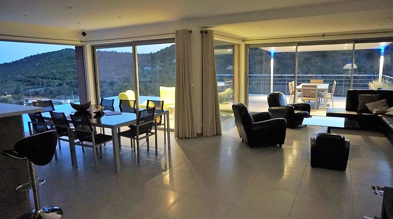 Intérieur d’une villa d’architecte à Conca Intérieur d'une villa moderne avec salon et salle à manger, grandes baies vitrées et vue sur la montagne.
