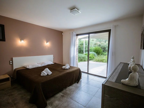 Chambre d'une villa contemporaine à Porto-Vecchio avec accès à un jardin.