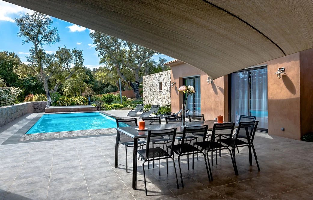 Terrasse de villa contemporaine à Porto-Vecchio Terrasse d'une villa contemporaine avec piscine, chaises longues et table à manger, Porto-Vecchio.