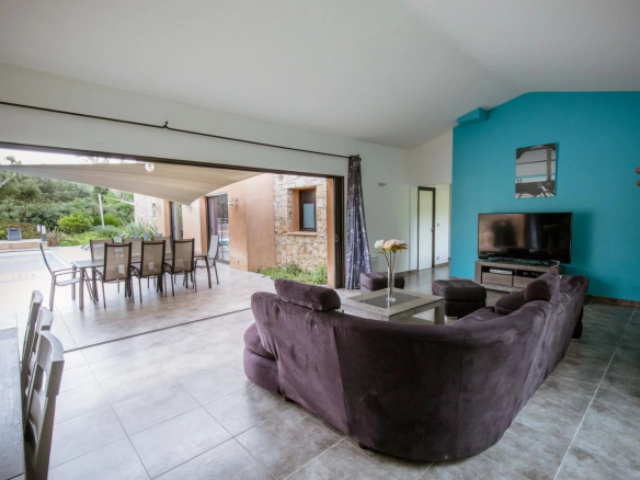 Intérieur d'une villa contemporaine avec un salon spacieux et accès à la terrasse extérieure.