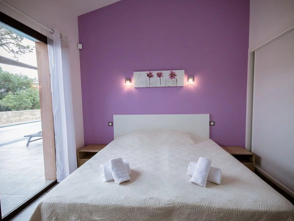 Chambre d'une villa contemporaine à Porto-Vecchio avec murs violets et lit double.