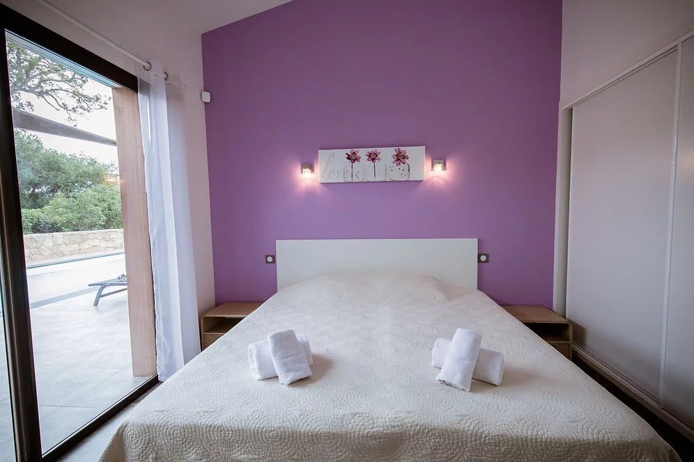 Chambre moderne à Porto-Vecchio Chambre d'une villa contemporaine à Porto-Vecchio avec murs violets et lit double.