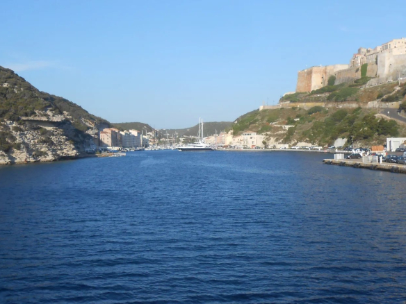 View of the sea and cliffs at Bonifacio, with boats in the port.