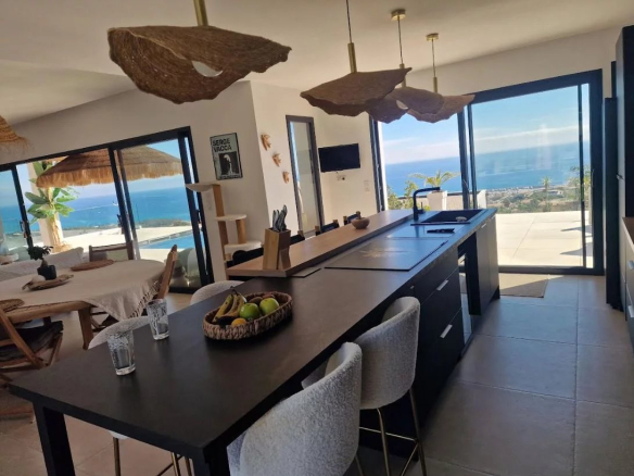 Modern interior of a villa with sea views in Sari-Solenzara, open kitchen and dining room.