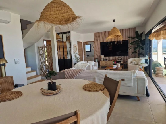 Interior of a modern villa with living room, dining table and warm decor.