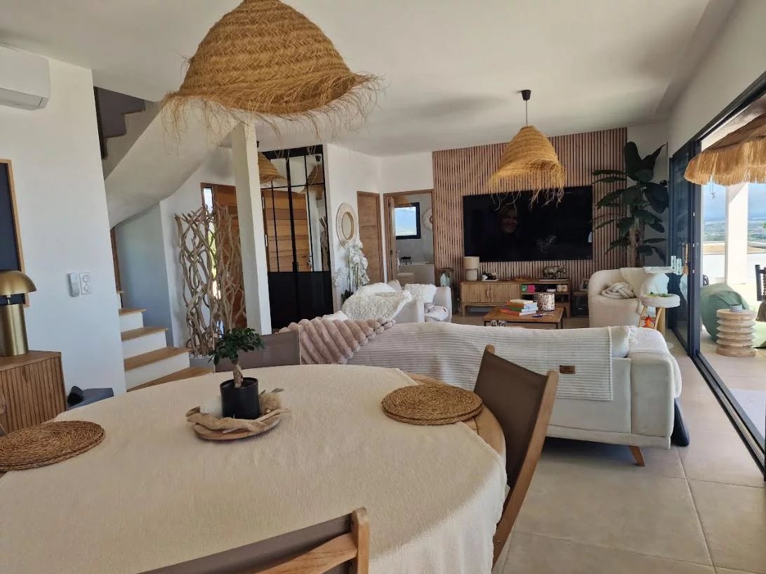 Interior of a villa in Sari-Solenzara Interior of a modern villa with living room, dining table and warm decor.
