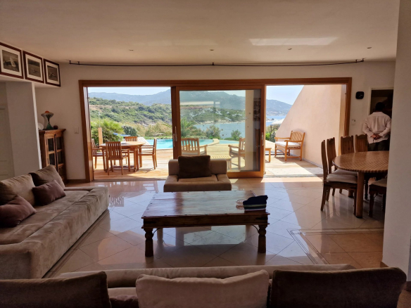 Intérieur d'une villa avec vue sur la mer, salon lumineux et accès à la terrasse.