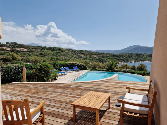 Vue sur la piscine à débordement et la mer depuis la terrasse d'une villa à Corbara.