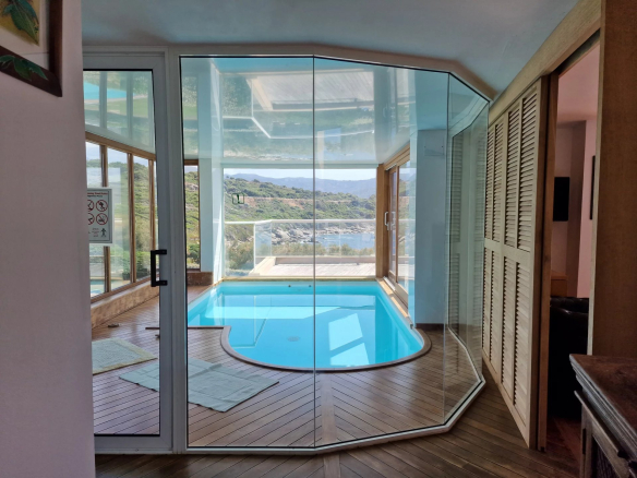 Intérieur d'une villa avec piscine vitrée et vue sur la mer.