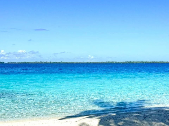 Plage de sable fin avec eau turquoise et ciel dégagé sur l'île de Takapoto.