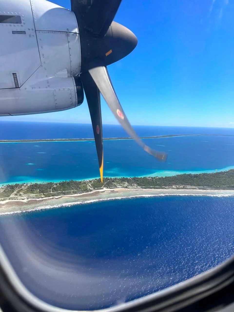 Vue aérienne de l'île de Takapoto avec un hélice d'avion en premier plan.