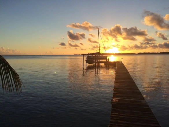 Coucher de soleil sur un ponton à Takapoto, îles Tuamotu, avec un bateau amarré.