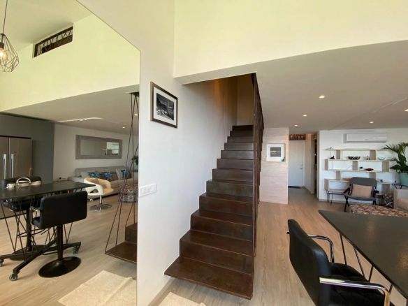 Intérieur d'un appartement style loft avec escalier, mobilier moderne et décoration soignée à Papeete.