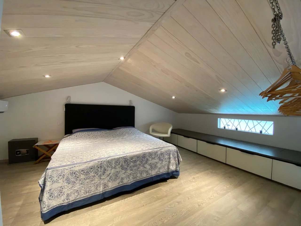Chambre de loft à Papeete Chambre d'un appartement style loft à Papeete, avec un lit, un banc et un éclairage moderne.