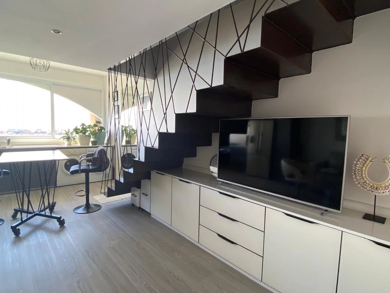 Appartement style Loft à Papeete Intérieur d'un appartement style loft avec un escalier moderne et un téléviseur.
