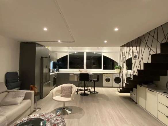 Intérieur d'un appartement style loft à Papeete, avec cuisine moderne et salon lumineux.