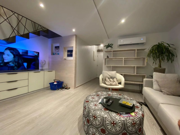 Intérieur d'un appartement style loft à Papeete, avec salon moderne et télévision.