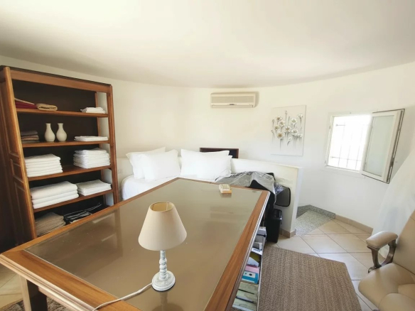 Chambre d'une demeure en pierre avec mobilier en bois et literie blanche.