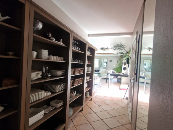 Intérieur d'une propriété avec des étagères chargées de vaisselle et un espace de vie lumineux.