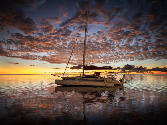 Catamaran amarré sur une mer calme au coucher du soleil à Tikehau, Polynésie française.