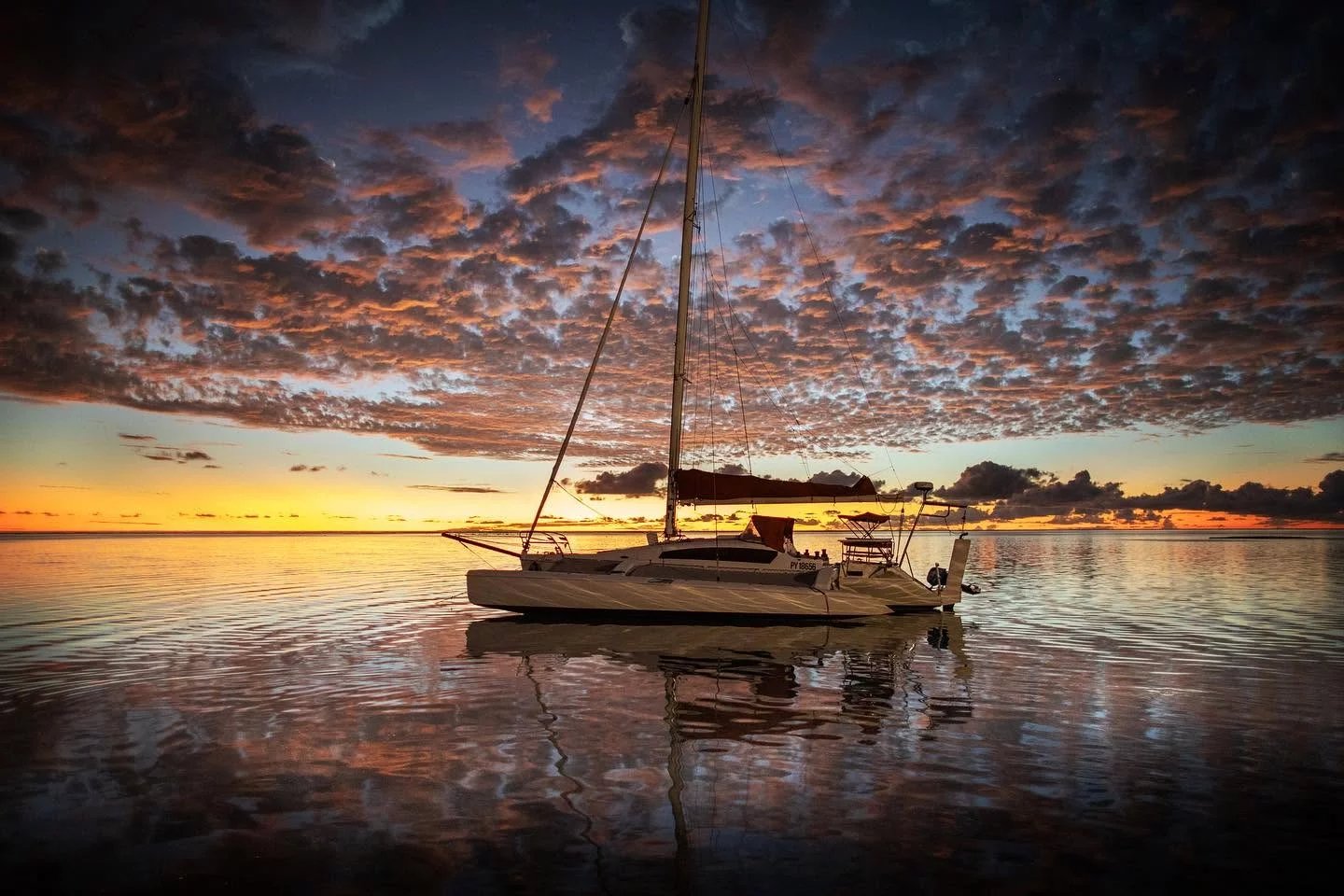 Coucher de soleil sur un catamaran à Tikehau Catamaran amarré sur une mer calme au coucher du soleil à Tikehau, Polynésie française.