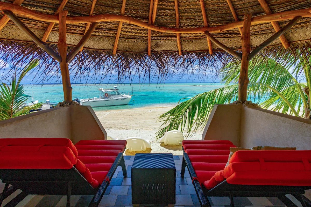 Éco-lodge de luxe à Tikehau Vue depuis un abri en bord de mer avec des chaises longues rouges et la mer en arrière-plan à Tikehau, Polynésie française.