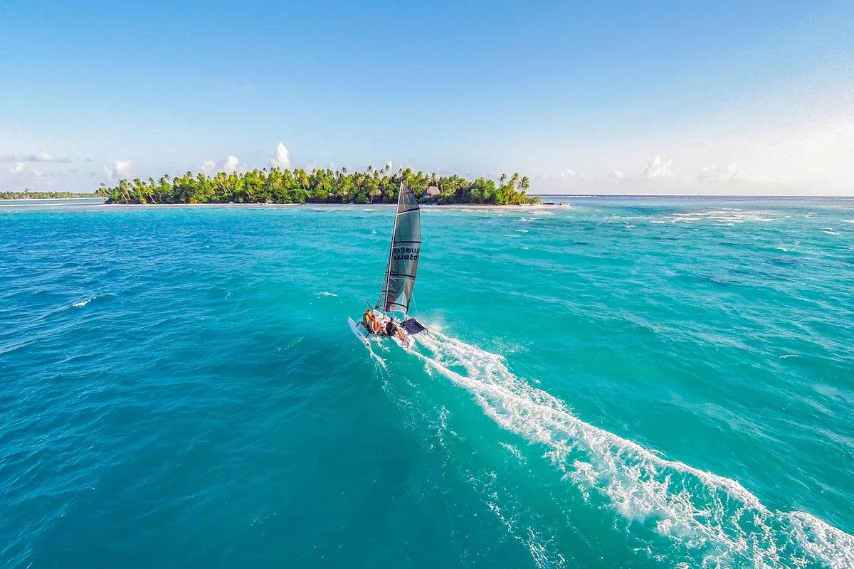 Catamaran à Tikehau Un catamaran naviguant sur des eaux turquoise près d'une île tropicale à Tikehau, Polynésie française.
