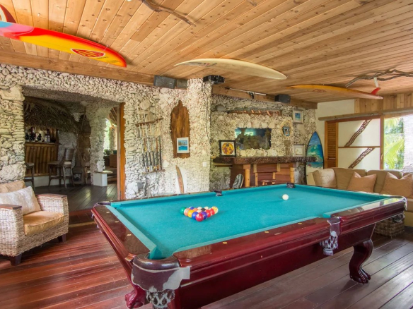 Salle de jeux avec table de billard et décoration en pierre dans un éco-lodge de luxe à Tikehau.