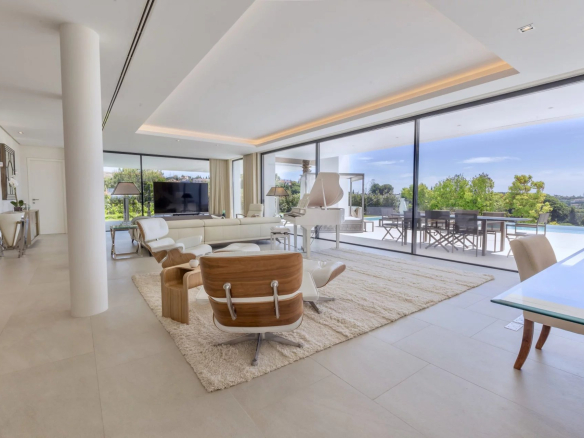 Intérieur d'une villa moderne à Los Flamingos, Marbella, avec salon lumineux et vue sur la piscine.