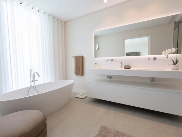 Salle de bain moderne avec baignoire et miroir lumineux dans une villa de luxe.