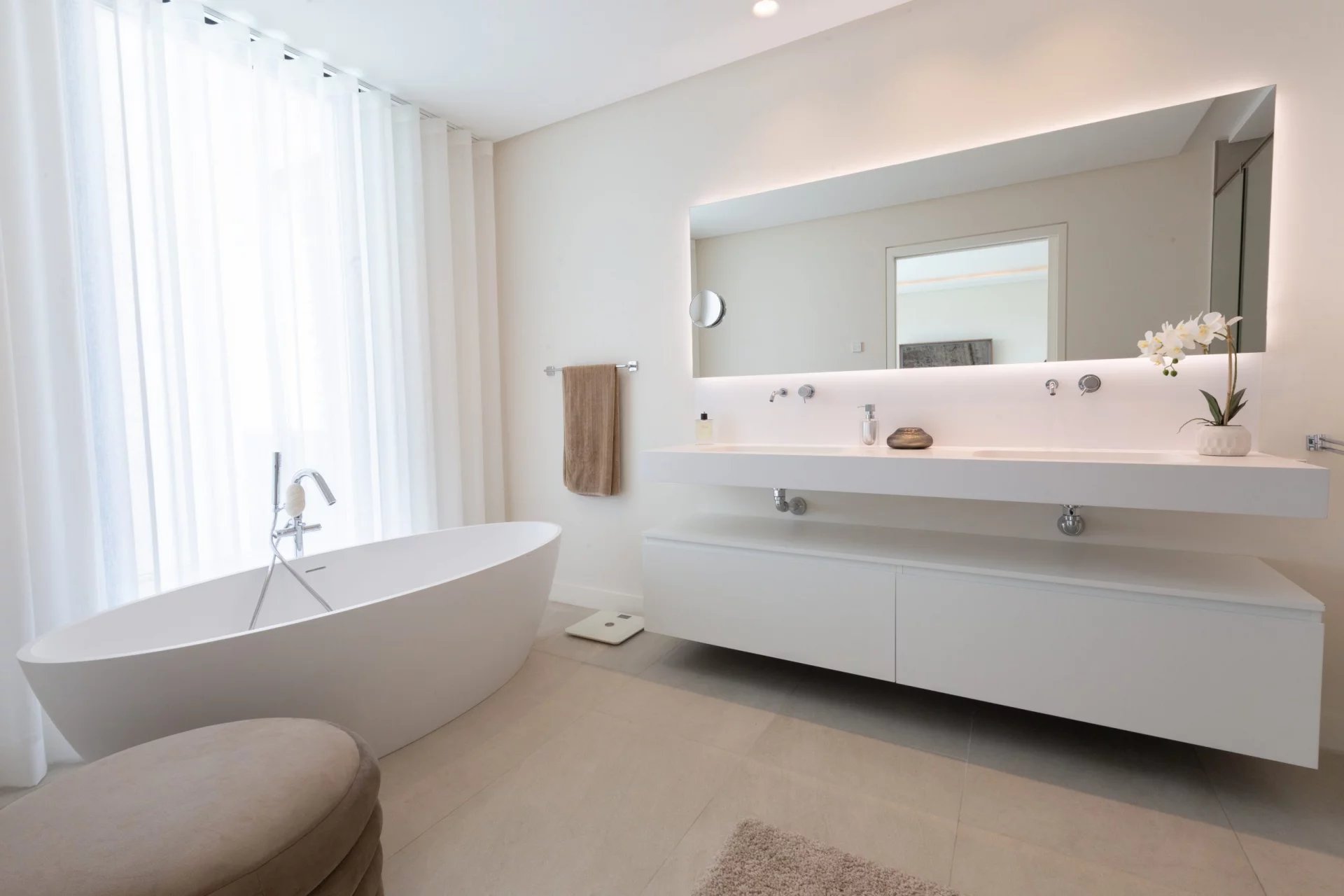 Salle de bain moderne avec baignoire et miroir lumineux dans une villa de luxe.