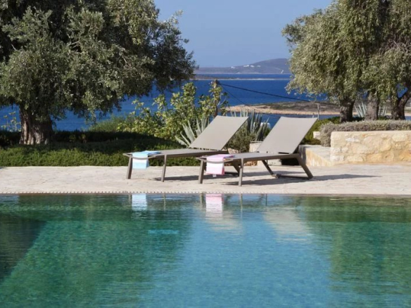 Chaises longues au bord d'une piscine avec vue sur la mer Égée à Paros.
