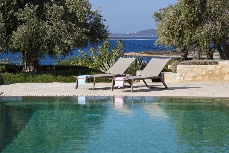 Villa d’exception à Paros Chaises longues au bord d'une piscine avec vue sur la mer Égée à Paros.