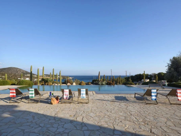 Vue panoramique de la piscine et du paysage à Farangas, Paros, avec des transats en bord de mer.