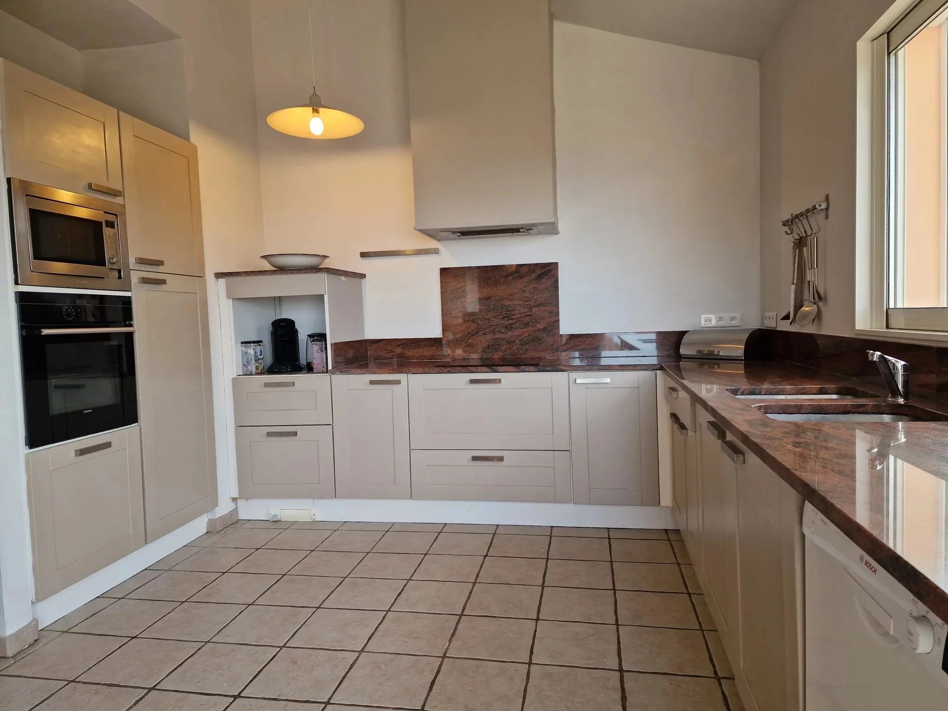 Kitchen of the property in Conca Modern kitchen with light-colored furniture and a marble worktop, tiled floor.
