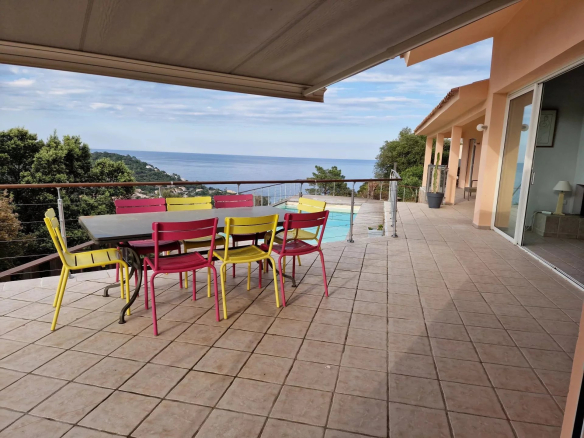 Terrace with table and colorful chairs overlooking the sea in Conca.