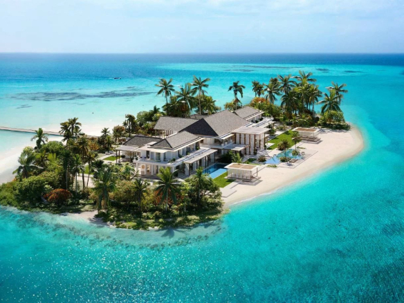Vue aérienne d'une villa de luxe sur une île aux Maldives, entourée d'eau turquoise et de palmiers.