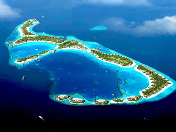 Vue aérienne d'un archipel de villas de luxe aux Maldives, entouré d'eau turquoise.