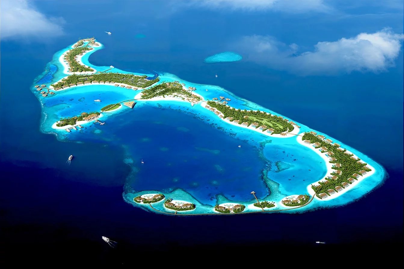 Vue aérienne d'un archipel de villas de luxe aux Maldives, entouré d'eau turquoise.