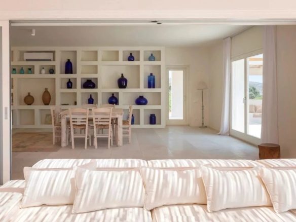 Intérieur d'une villa de luxe à Antiparos, avec un salon lumineux et une salle à manger décorée de vases en verre.