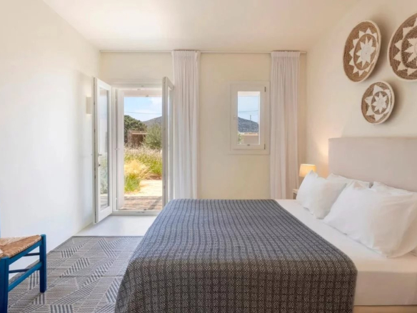 Chambre d'une villa de luxe à Antipaxos, avec un lit, des coussins et des décorations murales.