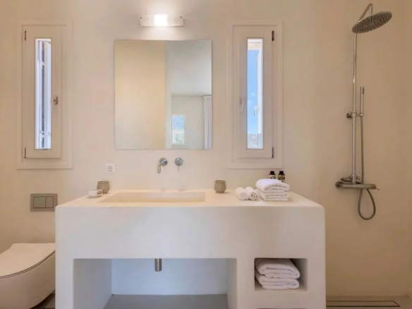 Salle de bain moderne avec lavabo, miroir et douche dans une villa de luxe à Antipaxos, Grèce.