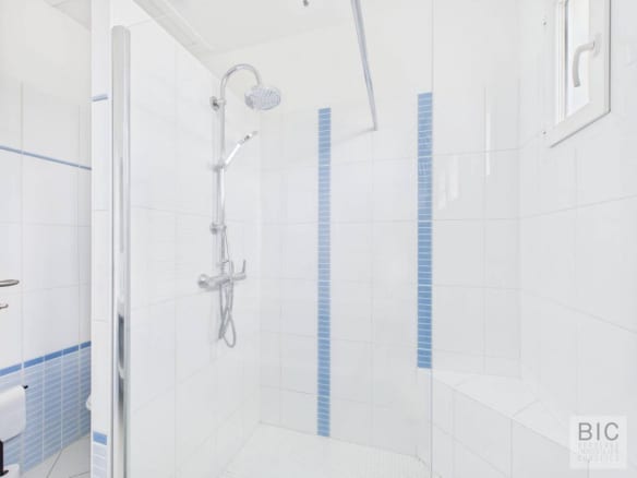 Douche moderne dans une salle de bain avec carrelage blanc et bleu.