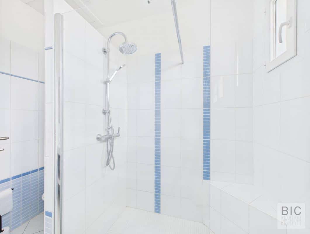 Douche moderne dans une salle de bain avec carrelage blanc et bleu.