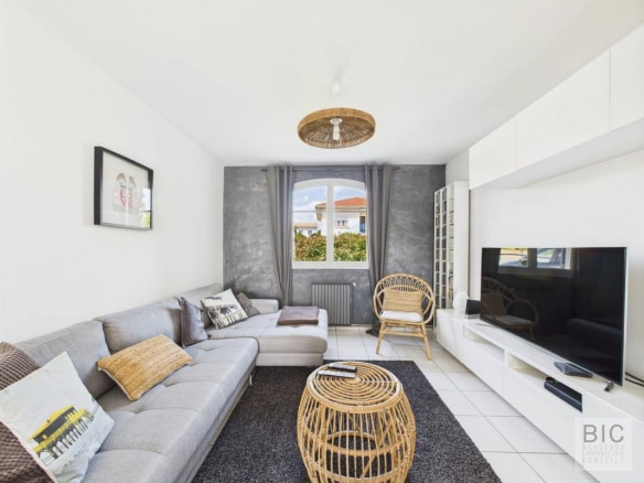 Salon lumineux d'une maison familiale à Mérignac avec canapé, table basse et télévision.