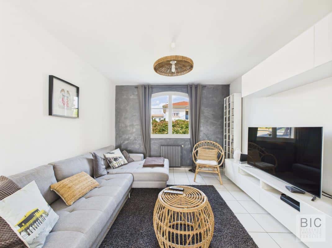 Salon lumineux d'une maison familiale à Mérignac avec canapé, table basse et télévision.