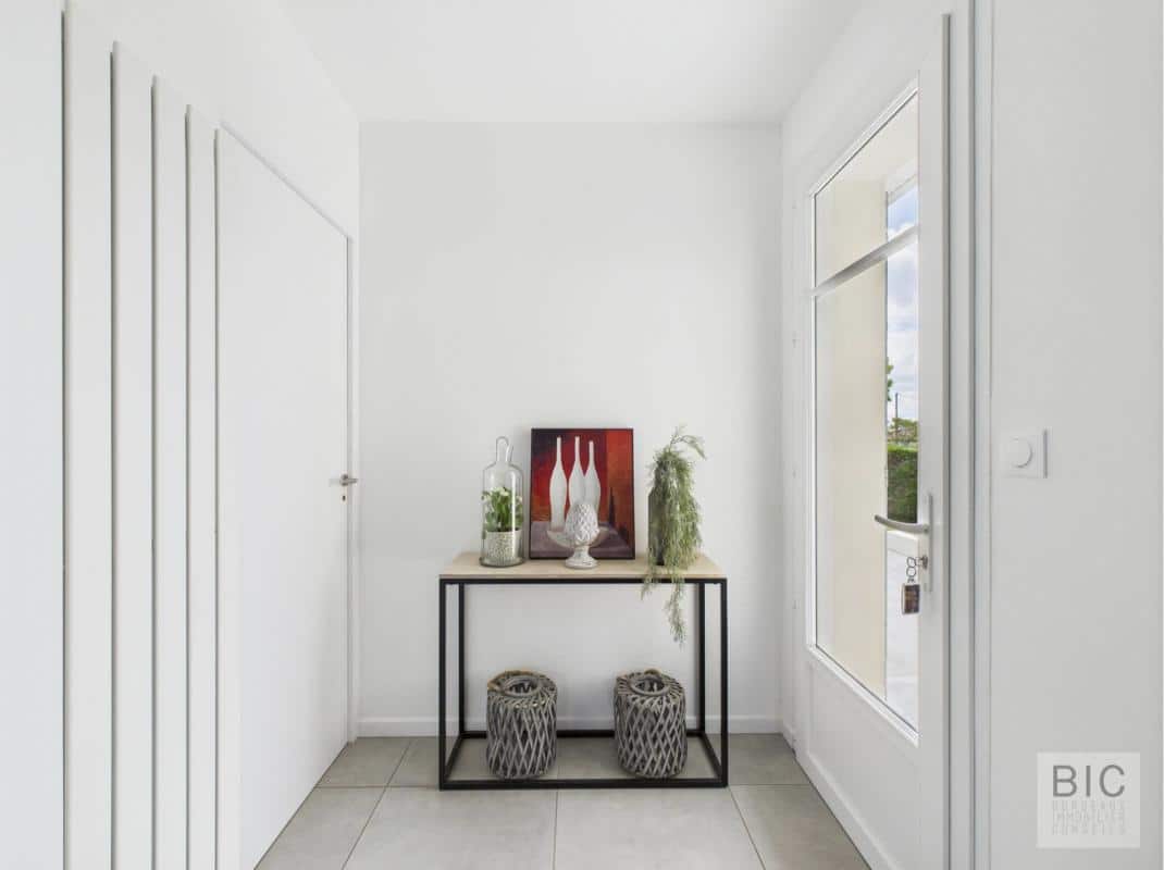 Entrée d'une maison familiale spacieuse avec meuble décoratif et fenêtres lumineuses.