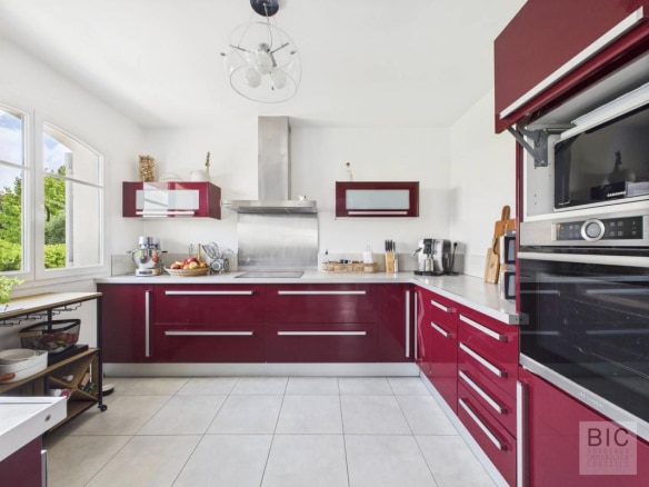 Cuisine moderne avec meubles rouges et équipements en inox dans une maison familiale.