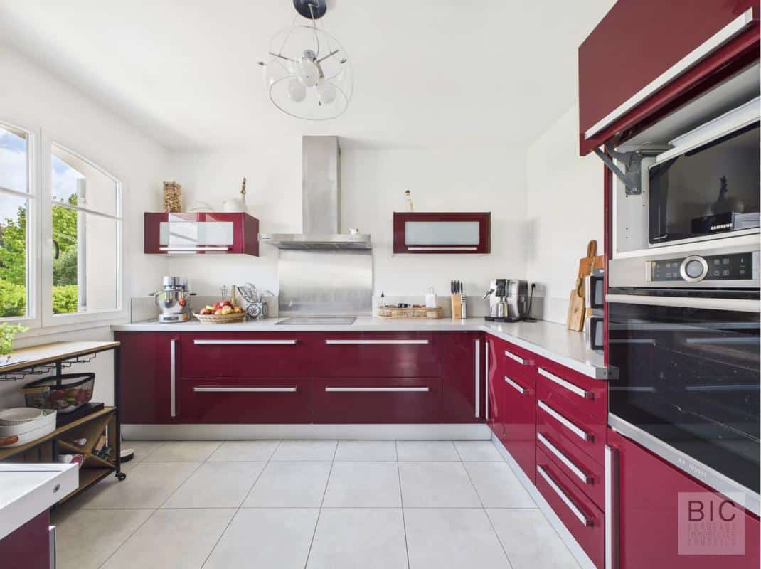Cuisine moderne avec meubles rouges et équipements en inox dans une maison familiale.