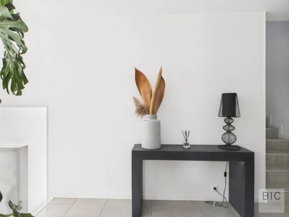 Intérieur d'une maison moderne avec un meuble noir, un vase et des plantes décoratives.